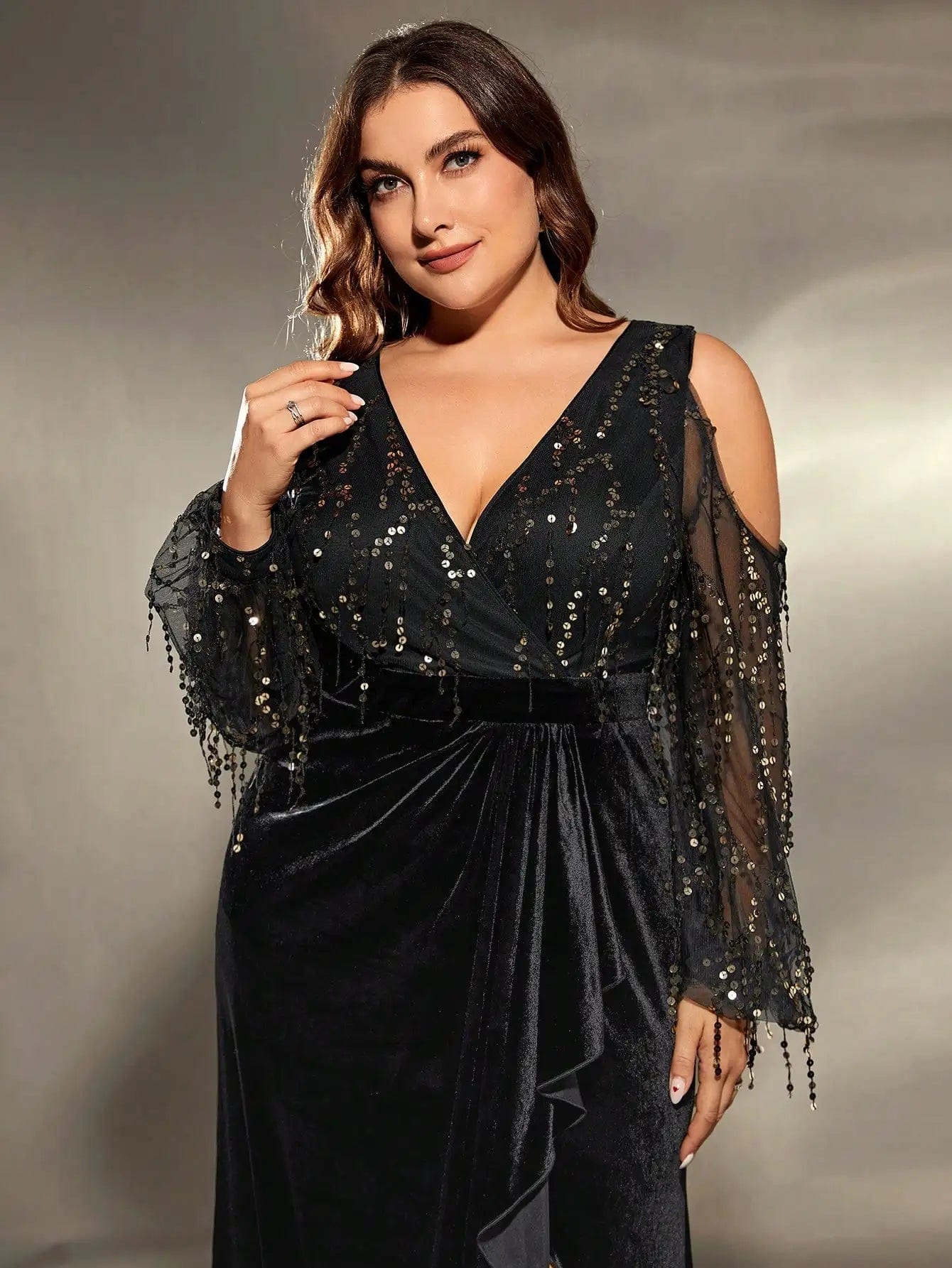 Robe de soirée grande taille noire fendue avec manches longues et détails pailletés pour gala ou événement chic.