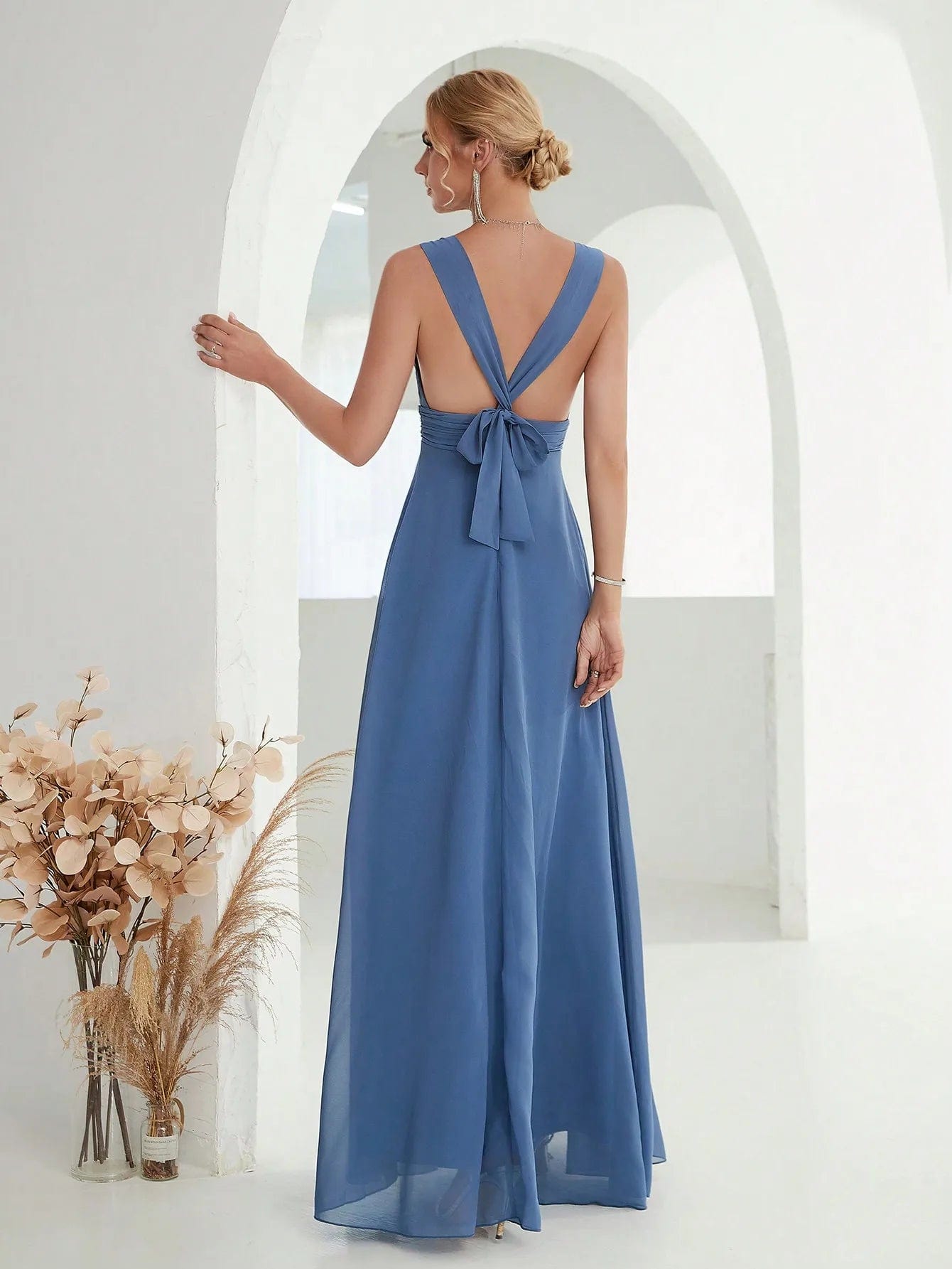 Robe demoiselle d'honneur bleue longue avec noeud au dos et silhouette trapèze pour mariage chic.