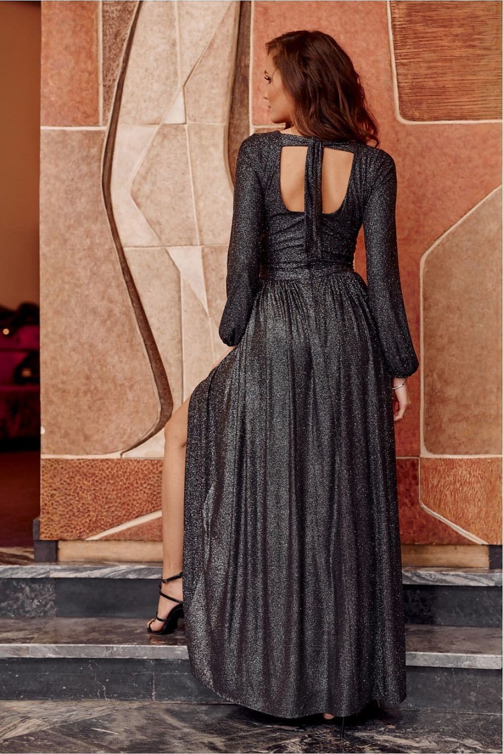 Robe de gala noire longue avec manches longues et dos nu, élégante pour soirées chic et évènements formels.