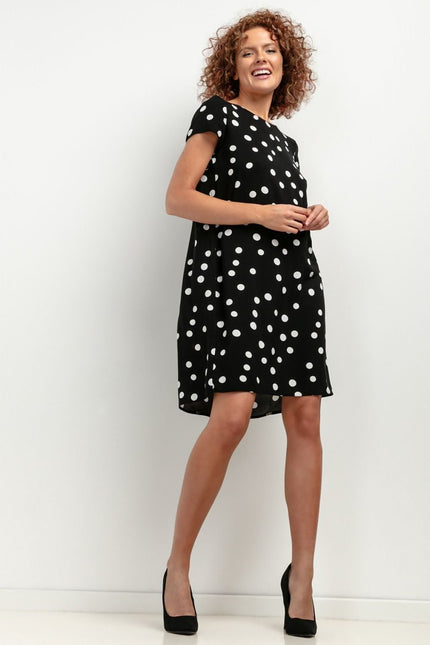 Robe noire à pois blancs, style casual chic, manches courtes, longueur midi, idéale pour soirée ou cocktail.