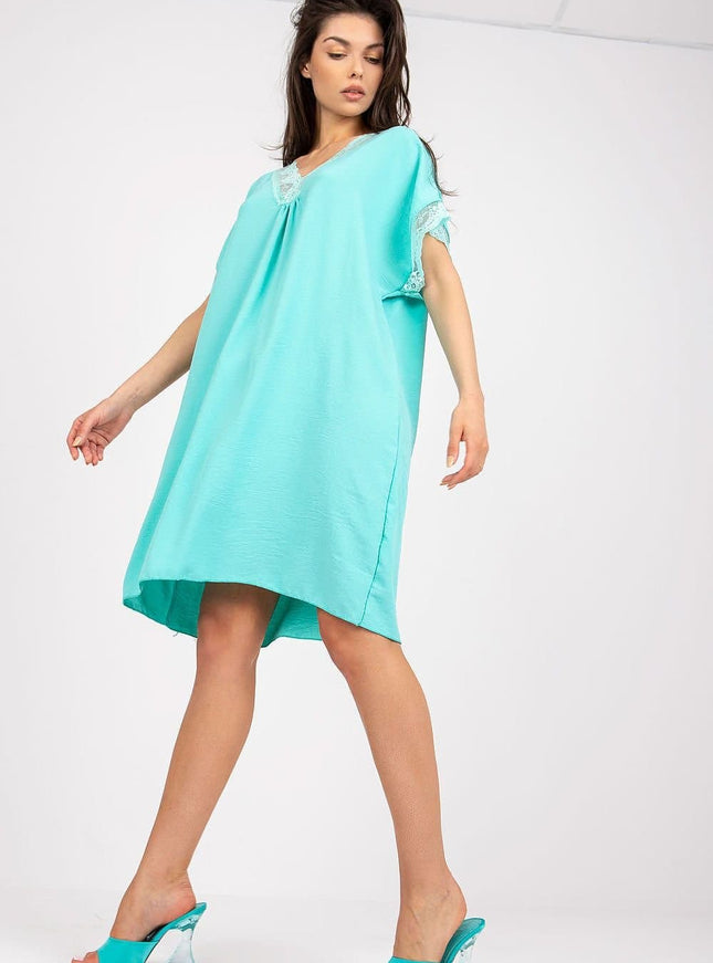 Robe d'été verte courte avec détails en dentelle, manches courtes et silhouette trapèze, idéale pour une soirée simple ou une balade à la plage.