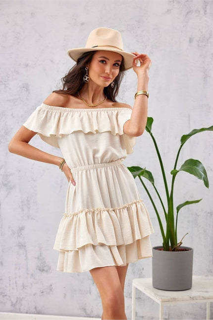 Robe de plage beige courte à épaules dénudées et à volants, parfaite pour une allure décontractée et féminine en journée estivale.