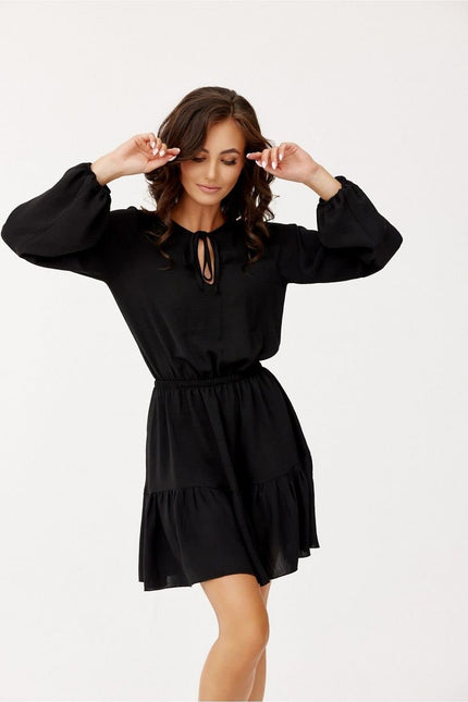 Robe soirée chic noire courte manches longues avec détail de découpe pour une élégance simple et moderne.