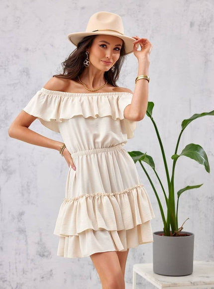 Robe de plage beige courte à épaules dénudées et à volants, parfaite pour une allure décontractée et féminine en journée estivale.