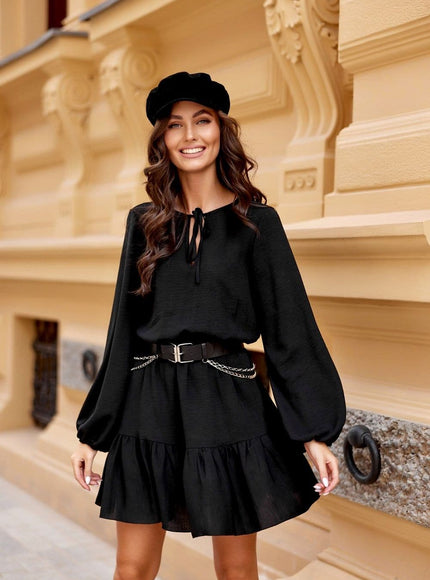 Robe soirée chic noire courte avec manches longues et ceinture, idéale pour cocktail ou événement élégant.