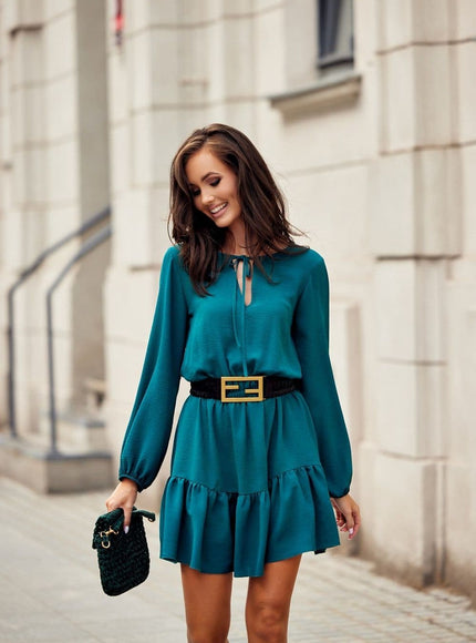 Robe verte chic courte à manches longues idéale pour cocktail ou soirée, avec ceinture noire pour une silhouette élégante.