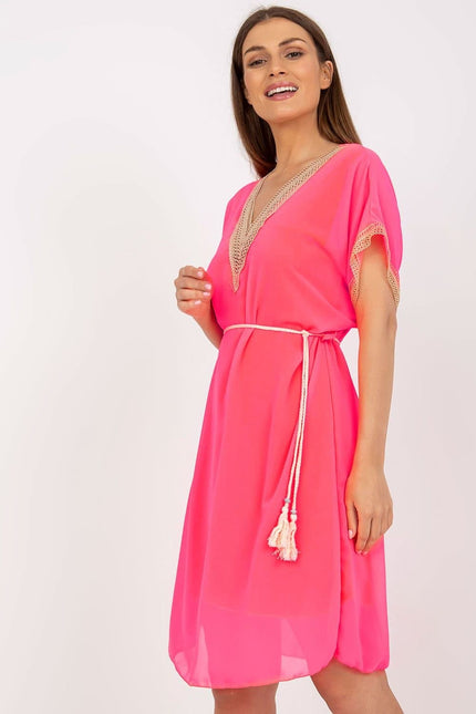 Robe rose de plage à manches courtes et détails en crochet avec ceinture à pompons, style fluide pour été décontracté.