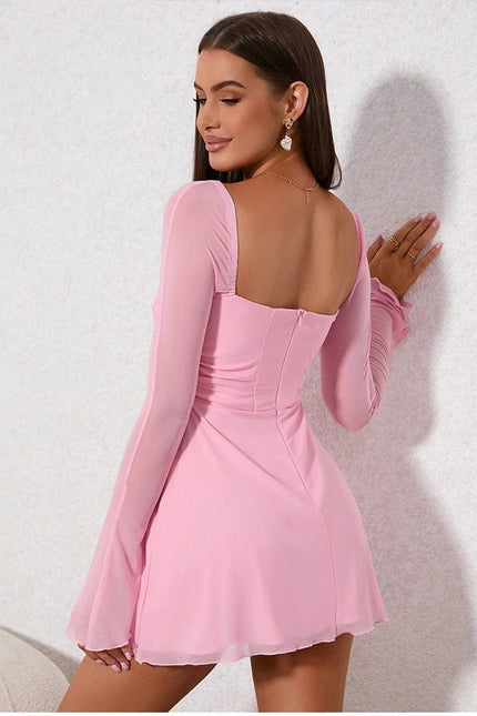 Robe courte rose poudré, élégante pour soirée chic, avec manches longues et décolleté séduisant.