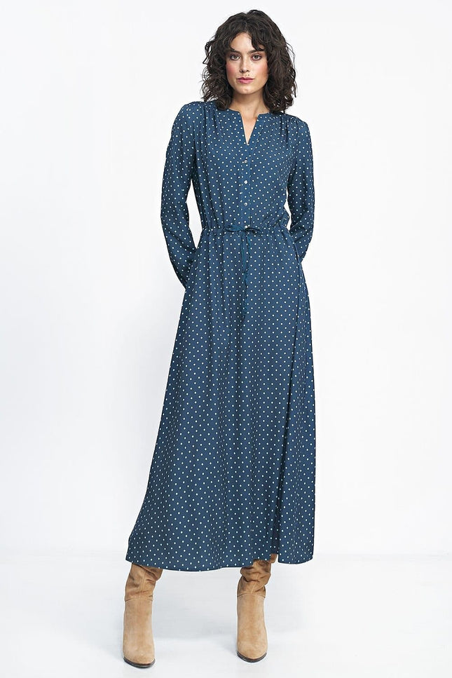 Robe longue bleue à pois blancs avec manches longues et boutons pour un style casual ou pour travail, silhouette droite et ceinturée.