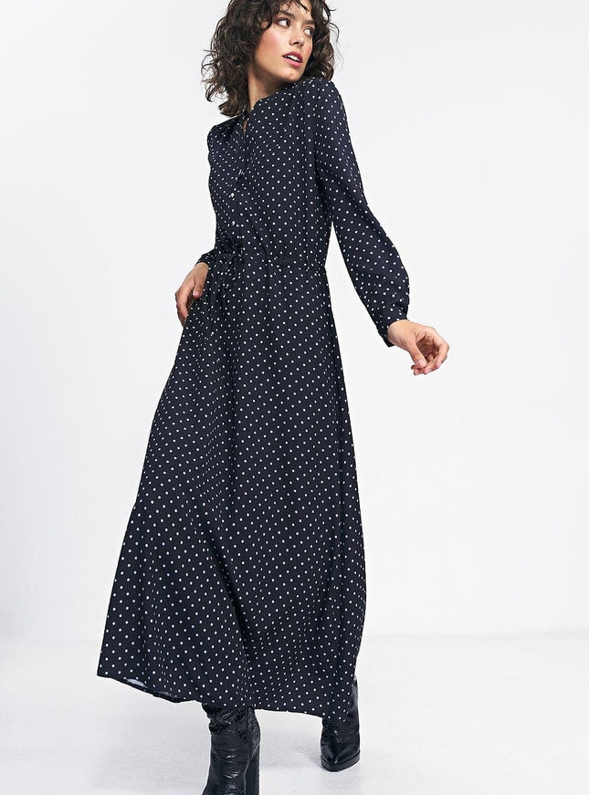 Robe noire à pois longue avec manches longues pour soirée chic ou cocktail, silhouette trapèze et élégante.