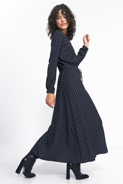 Robe noire à pois longue avec manches longues, ceinturée, idéale pour soirée ou événement cocktail, élégante et fluide.