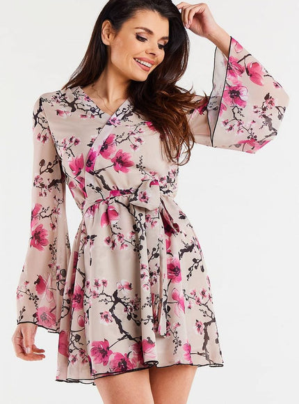 Robe fleurie chic manches longues midi idéale pour cocktail ou soirée, couleur rose sur fond beige.