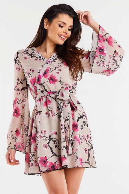 Robe fleurie chic manches longues midi idéale pour cocktail ou soirée, couleur rose sur fond beige.