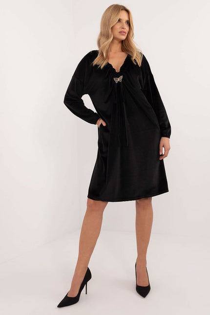 Robe noire courte de soirée chic avec manches longues et détail papillon, idéale pour cocktail ou nouvel an.