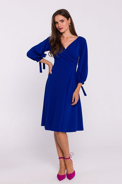 Robe bleue midi chic pour cocktail avec manches longues et détail nœud, silhouette droite.