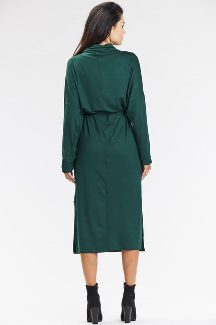 Robe verte longue à manches longues et ceinture, idéale pour soirée chic ou événement d'hiver.